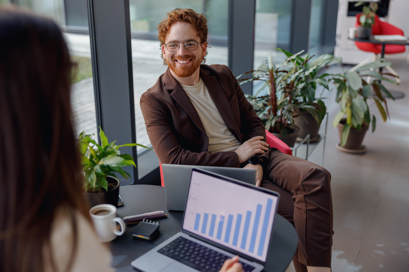 Manager smiles during a review, the sales charts show an uptrend on their computer